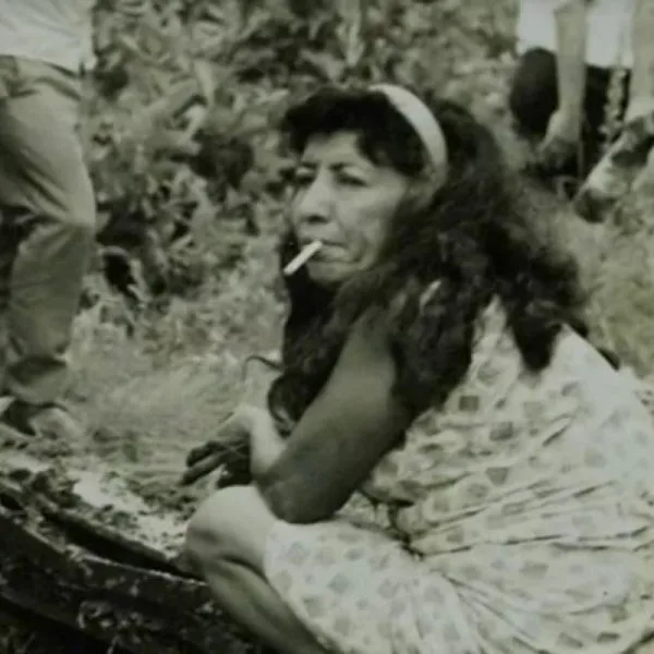 Célia de Souza conhecida como "Bruxa da Sapolândia", de cócoras, fumando, em meio à escavação pelos restos mortais de crianças. (Foto: reprodução de processo)