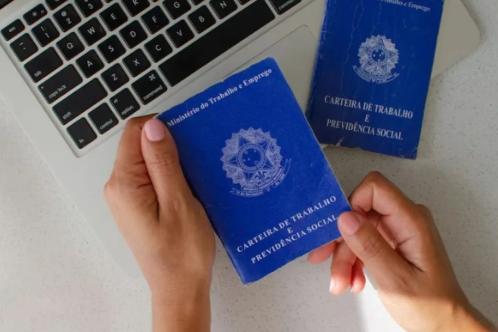 Pessoas segurando uma carteira de trabalho, vagas de emprego